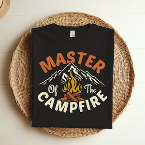 May include: Black t-shirt with a vintage-style graphic that says "Master of the Campfire". The graphic features a mountain range with a campfire in front of it.