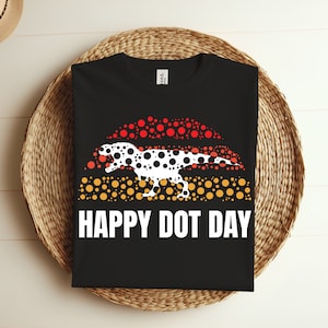 Puede incluir: Camiseta negra con una silueta de dinosaurio blanca hecha de puntos rojos, naranjas y amarillos. El texto "HAPPY DOT DAY" está impreso debajo del dinosaurio.