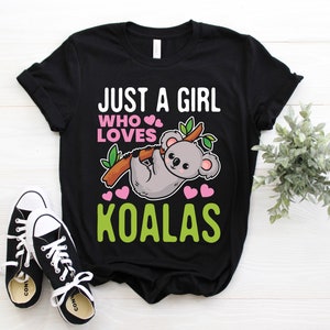 May include: Black t-shirt with the text "Just a girl who loves koalas" in green and pink. A cartoon koala is holding onto a branch with pink hearts around it.
