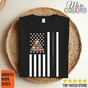 May include: Black t-shirt featuring a graphic of the American flag with a pool ball rack replacing the stars and stripes. Two pool cues are on the right. The shirt has the text "More Colors", "Adults Kids Sizes", and "Top-Rated Store".