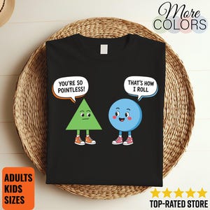 May include: A black t-shirt featuring a green triangle character and a blue circle character. The triangle says, "YOU'RE SO POINTLESS!" and the circle replies, "THAT'S HOW I ROLL." Both characters have arms, legs, and wear sneakers on their feet.