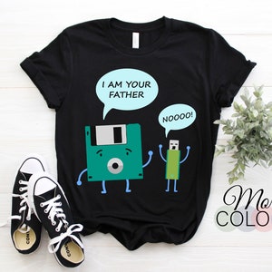 May include: Black t-shirt featuring a cartoon floppy disk saying "I AM YOUR FATHER" to a USB drive that replies "NOOOO!". The shirt is paired with black and white sneakers. The words "More Colors" are also visible.