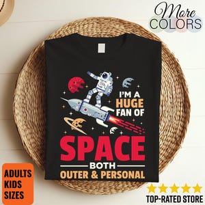 以下が含まれることがあります： 宇宙をテーマにした黒いTシャツ。ロケットに乗った宇宙飛行士のグラフィックが特徴です。「I'm a huge fan of space both outer & personal」の文字。大人と子供のサイズがあります。
