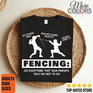 May include: Black t-shirt with a white fencing graphic and text. The graphic shows two fencers with the phrases "Hit others first," "Run with sharp objects," and "Always start it." The shirt also says "FENCING: Do everything that your parents told you not to do."
