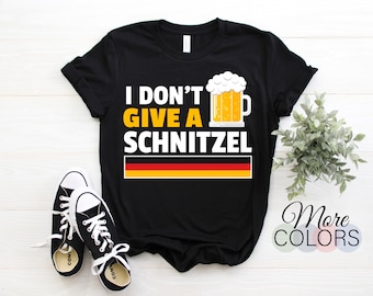 May include: Black t-shirt with the text "I don't give a schnitzel" and a cartoon beer mug. The text is in white and yellow, and the beer mug is yellow with white foam. The German flag is below the text.