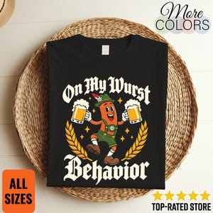 Può includere: Una t-shirt nera con la grafica di una salsiccia cartoon che indossa un cappello verde e lederhosen, mentre tiene due boccali di birra. Il testo On My Wurst Behavior è in carattere gotico bianco, circondato da spighe di grano gialle.