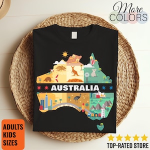 Op de afbeelding: Zwart t-shirt met een kleurrijke kaart van Australië, met iconische afbeeldingen en het woord "AUSTRALIA". Het ontwerp bevat een kangoeroe, koala en andere Australische symbolen. Het shirt heeft ook de tekst "More Colors", "Adults Kids Sizes" en "Top-Rated Store".