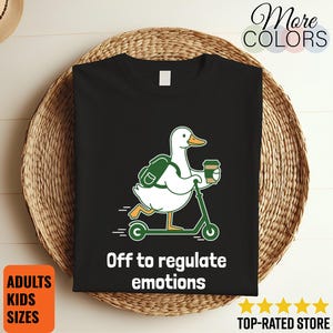 May include: Black t-shirt with a cartoon duck on a green scooter, holding a coffee cup and backpack. The text says "Off to regulate emotions." The shirt is available in adult and kids sizes.