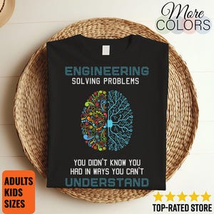 以下が含まれることがあります： 「ENGINEERING SOLVING PROBLEMS」と「YOU DIDN'T KNOW YOU HAD IN WAYS YOU CAN'T UNDERSTAND」の文字が入った黒いTシャツ。デザインは、カラフルな部分と青い回路基板の半分に分かれた脳のグラフィックです。「ADULTS KIDS SIZES」が含まれています。