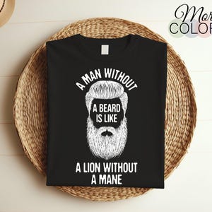 Puede incluir: Camiseta negra de cuello redondo con texto blanco y un gráfico de barba. El texto dice: «UN HOMBRE SIN BARBA ES COMO UN LEÓN SIN MELENA». La camiseta se muestra sobre una cesta tejida.