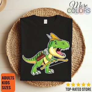 May include: Black t-shirt featuring a cartoon green dinosaur archer with a yellow hat and bow and arrow. The shirt has the text "More Colors" and "Top-Rated Store". The shirt is available in adult and kids sizes.