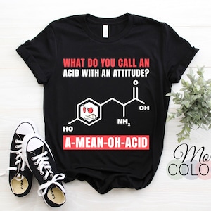 May include: Black t-shirt with a white graphic that says "What do you call an acid with an attitude?" and shows a chemical formula with a cartoon face. The text below the formula says "A-MEAN-OH-ACID".