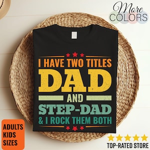 Pode incluir: Camiseta preta com o texto "I HAVE TWO TITLES DAD AND STEP-DAD & I ROCK THEM BOTH" em amarelo, laranja e verde. A camisa é exibida em uma cesta de vime. As palavras "ADULTS KIDS SIZES" estão em uma caixa laranja.