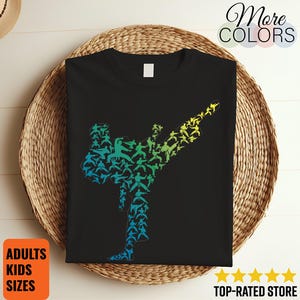 Può includere: Una t-shirt nera con una grande grafica composta da molte piccole sagome di artisti marziali in varie pose. Le sagome sono disposte a formare la figura di un grande calcio, con una sfumatura di colore che passa dal blu al verde fino al giallo.