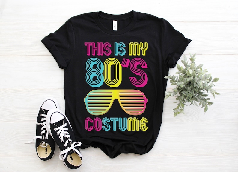 K&ouml;nnte beinhalten: Schwarzes T-Shirt mit dem Text "This is my 80's Costume" in bunter Retro-Schrift. Der Text ist von einer bunten Sonnenbrille umgeben.