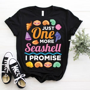 May include: Black t-shirt with a colourful seashell design and the text "Just One More Seashell I Promise".
