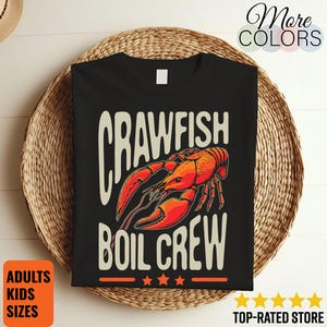 Może przedstawiać: Czarna koszulka z graficznym wzorem przedstawiającym czerwonego raka i napis "CRAWFISH BOIL CREW" w stylu vintage. Koszulka zawiera również napisy "ADULTS KIDS SIZES" i "TOP-RATED STORE".
