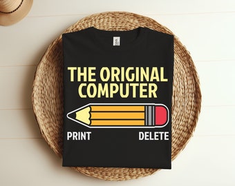 Może przedstawiać: Czarny T-shirt z napisem "THE ORIGINAL COMPUTER" w żółtych literach. Pod napisem znajduje się żółty ołówek z czerwoną gumką. Pod ołówkiem znajdują się słowa "PRINT" i "DELETE".