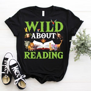 Puede incluir: Camiseta negra con un gr&aacute;fico verde que dice "Wild About Reading" con un libro y animales que rodean el texto.
