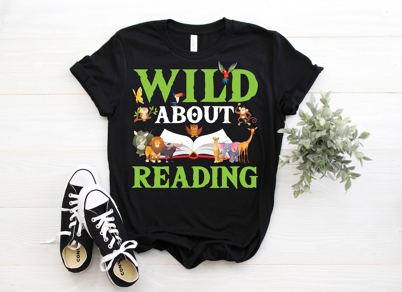 Puede incluir: Camiseta negra con un gr&aacute;fico verde que dice "Wild About Reading" con un libro y animales que rodean el texto.
