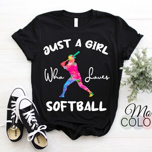 May include: Black t-shirt with a colorful graphic of a softball player and the text "Just a girl who loves softball".
