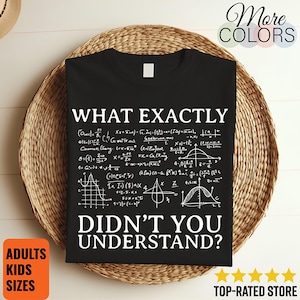 Può includere: Una t-shirt nera a maniche corte con testo bianco che recita WHAT EXACTLY DIDN'T YOU UNDERSTAND? sopra e sotto una complessa raccolta di equazioni matematiche, formule e vari grafici geometrici bianchi stampati sulla parte anteriore.