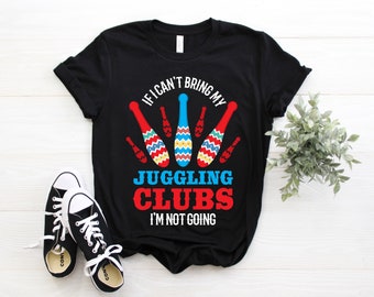 Könnte beinhalten: Schwarzes T-Shirt mit dem Text "IF I CAN'T BRING MY JUGGLING CLUBS I'M NOT GOING." Das Design zeigt rote, blaue und gelbe Jonglierkeulen. Ein Paar schwarz-weiße Turnschuhe befindet sich im Vordergrund.