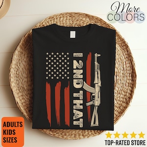 May include: Black t-shirt with a distressed American flag design, the text "I 2ND THAT", and a rifle graphic. The shirt also includes the text "ADULTS KIDS SIZES" and "TOP-RATED STORE".