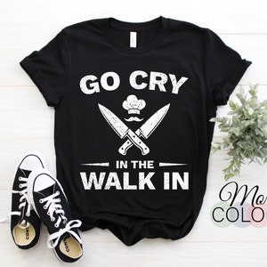 Könnte beinhalten: Schwarzes T-Shirt mit weißem Text, der "Go Cry In The Walk In" lautet, mit einem Kochhut und einer Grafik mit gekreuzten Messern.
