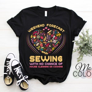 Peut inclure: T-shirt noir avec le texte "WEEKEND FORECAST SEWING WITH NO CHANCE OF HOUSE CLEANING OR COOKING." Le motif présente un cœur rempli d'objets de couture. Une paire de baskets noires et blanches est au premier plan.