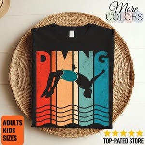 May include: Black t-shirt with a retro design featuring the word "DIVING" in orange letters and a silhouette of a diver mid-flip. The design includes red, orange, and blue stripes. Text on the shirt reads "ADULTS KIDS SIZES" and "TOP-RATED STORE".