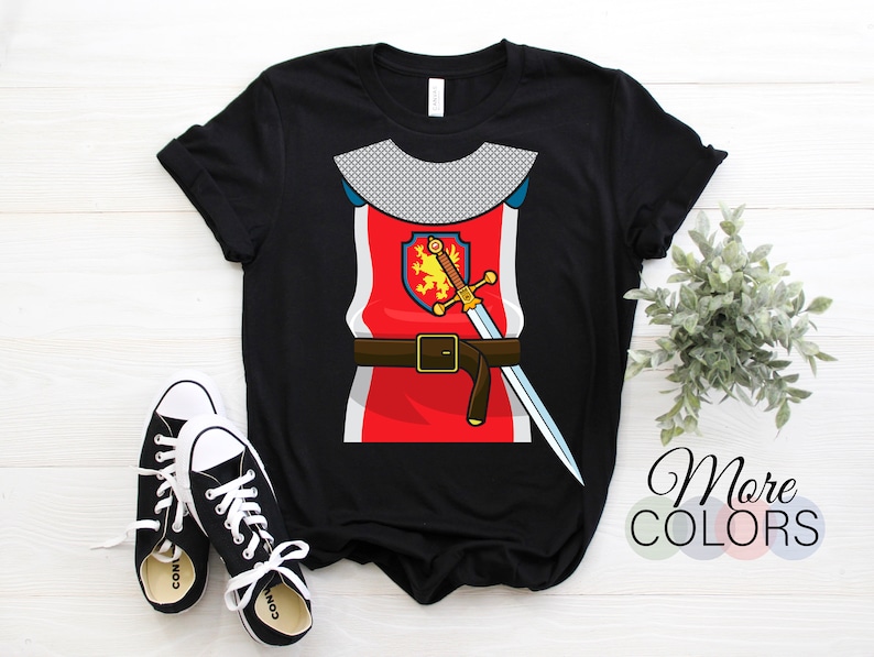 May include: Black t-shirt with a graphic of a knight in armor. The knight is wearing a red tunic with a gold belt and a sword. The knight's shield has a lion on it.