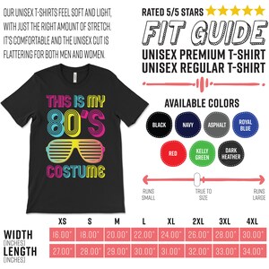 K&ouml;nnte beinhalten: Schwarzes Unisex-T-Shirt mit dem Text "This is my 80's Costume" in bunter Retro-Schrift. Das Shirt zeigt eine neonrosa und blaue Sonnenbrille. Eine Gr&ouml;&szlig;entabelle zeigt die Breite und L&auml;nge in Zoll f&uuml;r die Gr&ouml;&szlig;en XS bis 4XL.