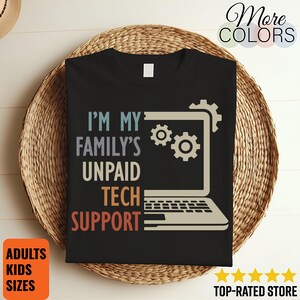 May include: Black t-shirt with the text "I'M MY FAMILY'S UNPAID TECH SUPPORT" in a multi-colored design. A laptop graphic is featured above the text. The shirt also has the words "ADULTS KIDS SIZES" and "TOP-RATED STORE" on the image.