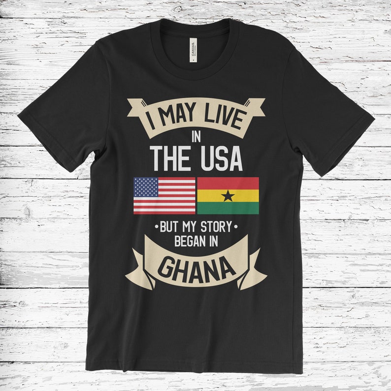 K&ouml;nnte beinhalten: Schwarzes T-Shirt mit einem Grafikdesign, das "Ich lebe vielleicht in den USA, aber meine Geschichte begann in Ghana" sagt. Die Grafik enth&auml;lt auch die amerikanische und ghanaische Flagge.