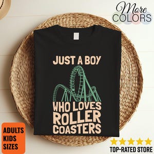 Puede incluir: Una camiseta negra con un gráfico verde claro de una montaña rusa. El texto impreso en color melocotón claro dice: JUST A BOY WHO LOVES ROLLER COASTERS. El diseño está centrado en la parte delantera de la camiseta, que tiene cuello redondo.