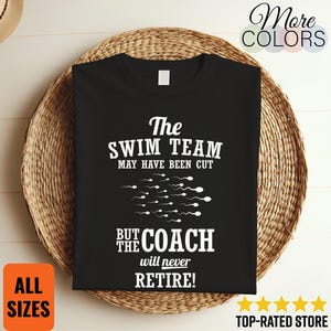 May include: Black t-shirt with white text: "The SWIM TEAM MAY HAVE BEEN CUT BUT THE COACH will never RETIRE!". The shirt is displayed on a woven, circular mat. Additional text includes "More COLORS", "ALL SIZES", and "TOP-RATED STORE".
