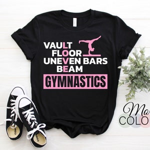 May include: Black t-shirt with the words "VAULT FLOOR UNEVEN BARS BEAM GYMNASTICS" in white text. The word "GYMNASTICS" is in pink. A pink silhouette of a gymnast performing on the uneven bars is above the text.