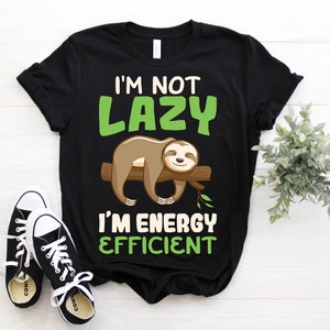 May include: Black t-shirt with a sloth graphic and the text "I'm not lazy, I'm energy efficient." The sloth is brown and resting on a brown log. Black and white sneakers are at the bottom.
