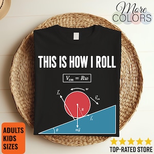 May include: A black t-shirt featuring the white text THIS IS HOW I ROLL above a physics diagram. The graphic displays a red circle rolling down a blue incline with labels including Vcm = Rw, fn, fs, mg, R, and theta, illustrating rotational motion.