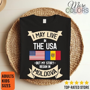 May include: Black t-shirt with the text "I MAY LIVE IN THE USA BUT MY STORY BEGAN IN MOLDOVA." The design includes the American and Moldovan flags. The shirt is displayed on a woven basket.