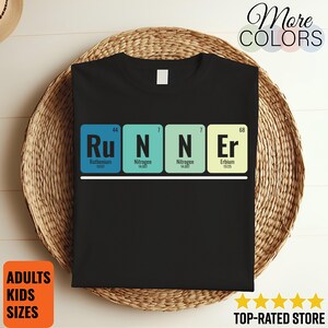Puede incluir: Camiseta negra con la palabra "RUNNER" deletreada con elementos de la tabla periódica: Rutenio, Nitrógeno, Nitrógeno y Erbio. La camiseta también tiene el texto "More Colors", "Adults Kids Sizes", y "Top-Rated Store".