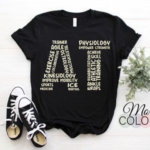 Pode incluir: Camiseta preta com a palavra "ATHLETE" escrita verticalmente usando palavras relacionadas ao treinamento atlético, como "treinador", "exercício", "fisiologia", "reabilitação" e "tornozelos".
