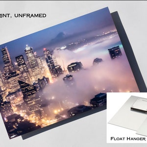 May include: A metal print of a city skyline at night with fog rolling in. The print is unframed and comes with a float hanger.