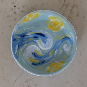 Może przedstawiać: Niebieska ceramiczna miska z wirującym wzorem malowanym na żółto, biało i niebiesko. Wzór przypomina słynne malowidło.