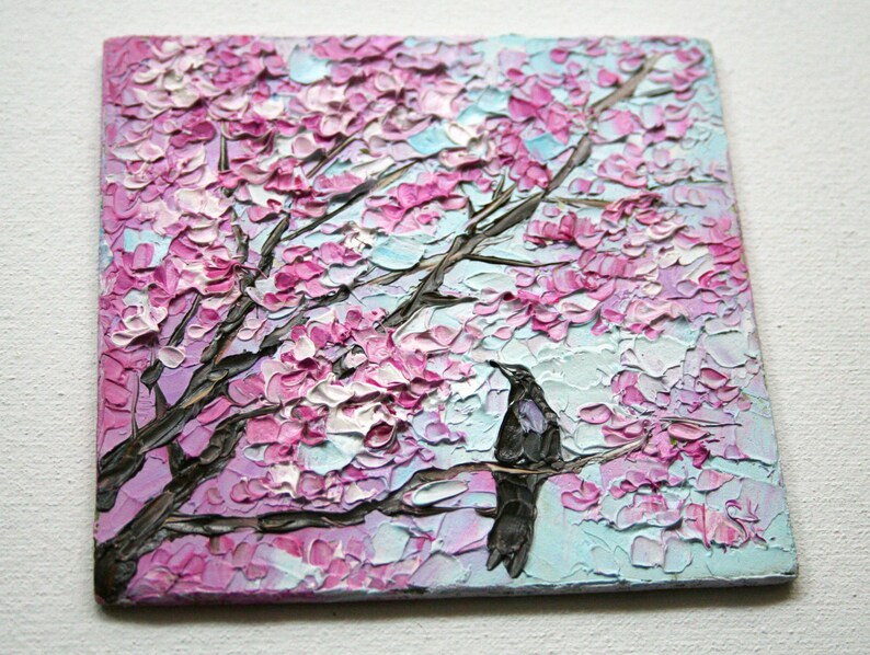 May include: A painting of a pink and white cherry blossom tree with a black bird perched on a branch. The background is a light blue sky.
