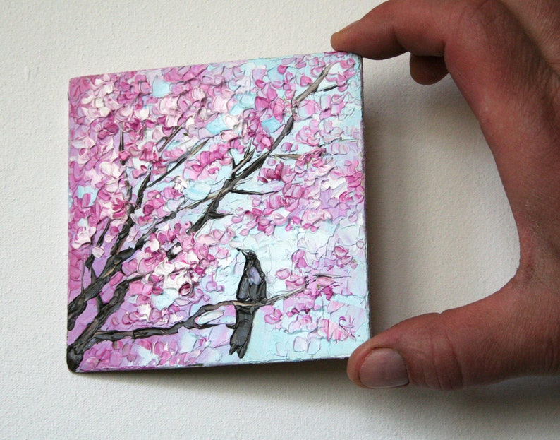 May include: A painting of a pink and white cherry blossom tree with two black birds perched on a branch. The painting is done in a textured style, giving the impression of brushstrokes.