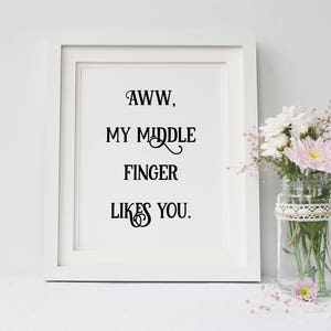 Pu&ograve; includere: Stampa incorniciata bianca con il testo "AWW, MY MIDDLE FINGER LIKES YOU."