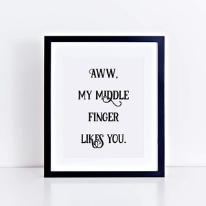 Pu&ograve; includere: Una stampa incorniciata nera con il testo "AWW, MY MIDDLE FINGER LIKES YOU."
