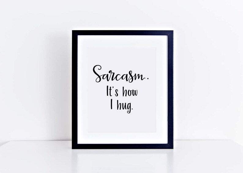 May include: A black framed print with white background and the text "Sarcasm. It's how I hug."